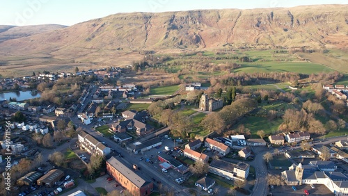 Low level aerial image of a Scottish village and glen surrounded by hills. A bright sunny day with a low sun casting long shadows and a restored church clock tower. photo