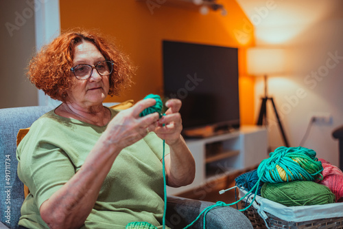 Mature woman holding knitting needles and knitting at home.