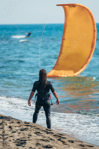 Woman wearing kite harness and a wetsuit on a beach