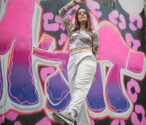 a modern young dancer poses in front of a street graffiti backdrop
