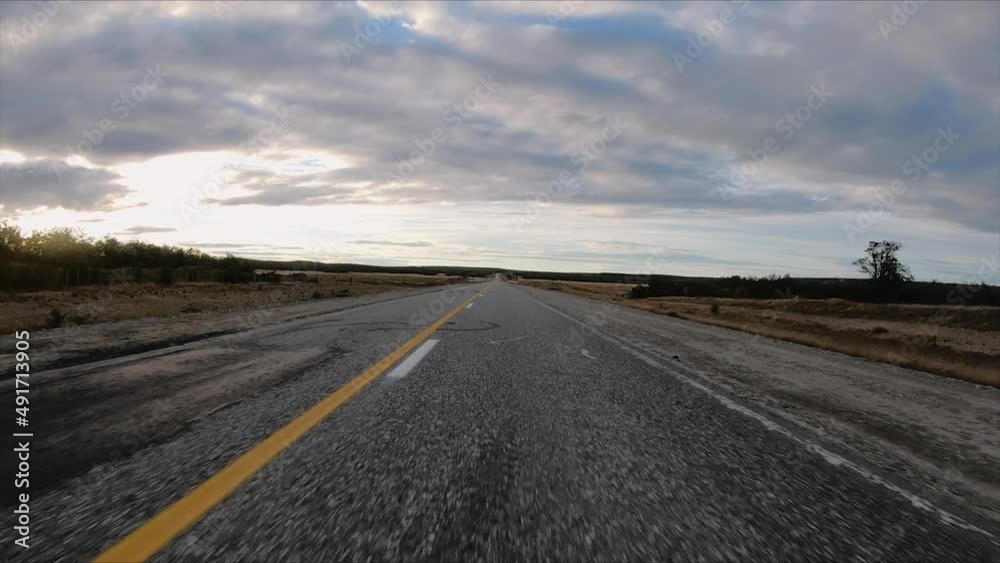 Traveling along the countryside route . Point of view of a car driving the asphalt road in the open field at sunset. Traveling along the countryside route . Point of view of a car driving the asphalt road in the open field at sunset.