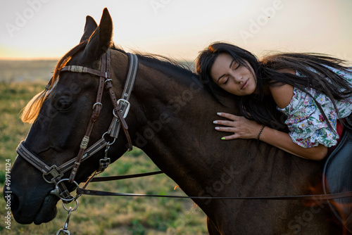 Girl with long black hair in the countryside. Ipadrome with horses. Rural landscapes, wild west. © Denys