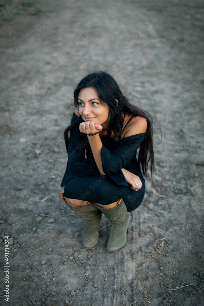 Girl with long black hair in the countryside. Ipadrome with horses. Rural landscapes, wild west.