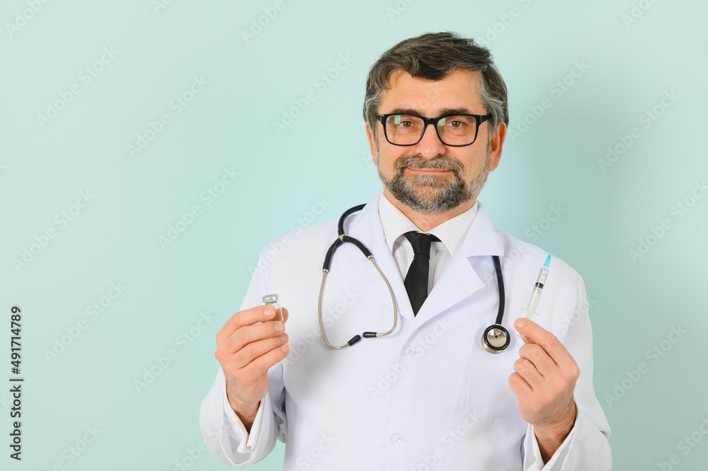 Vaccination against coronavirus. Testing COVID-19 vaccines. A male doctor fills a syringe the with a COVID-19 vaccine on a blue background. Doctor's hands hold a syringe close-up. Vaccination against coronavirus. Testing COVID-19 vaccines. A male doctor fills a syringe the with a COVID-19 vaccine on a blue background. Doctor's hands hold a syringe close-up.