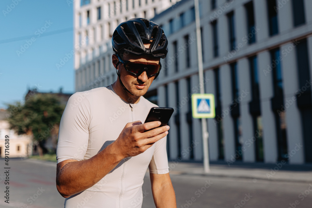 Man in sport clothes using mobile after cycling outdoors