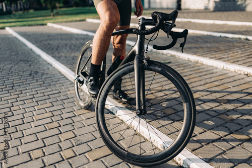 Cyclist in sport shoes sitting on black bike on fresh air © Tymoshchuk