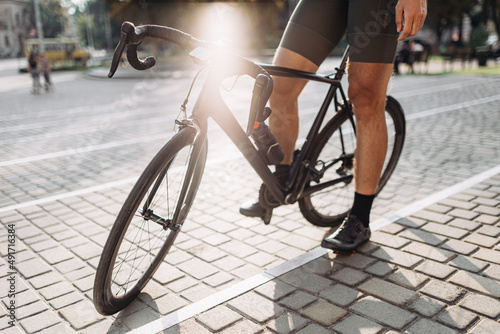 Close up of cyclish with strong legs standing with bike