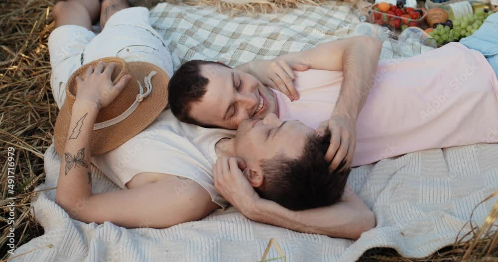 Couple of Two Men Gay Lying on Plaid at the Wheat Field looking at Each Other. Attractive Guys Spending Time on Nature, Feeling Love Enjoys Moments. Summertime Picnic. LGBT Representatives. Couple of Two Men Gay Lying on Plaid at the Wheat Field looking at Each Other. Attractive Guys Spending Time on Nature, Feeling Love Enjoys Moments. Summertime Picnic. LGBT Representatives.
