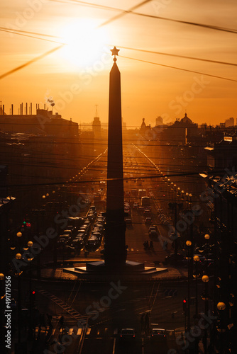 Sunset cityscape of perspective of Nevsky avenue in Saint Petersburg, Russia. On the foreground obelisk with a star. Traffic jam. Urban landscape with a lots of wires.