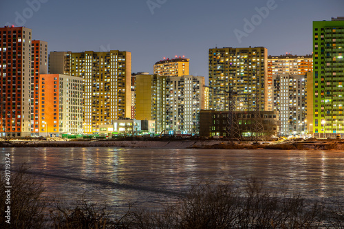 new residential complex under construction on Bank of the sea river in light of night lights reflected in ice