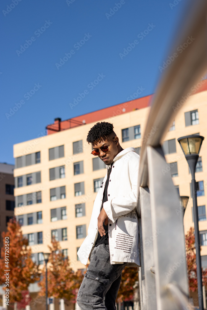 Latin black man with sunglasses on the street looking down. urban vertical portrait
