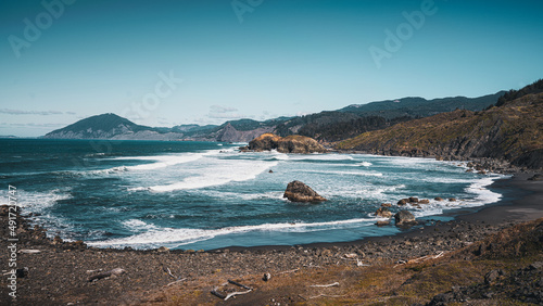 Crashing seaside waves foam and curl along the shore on a brisk moody day following the cost of Oregon 