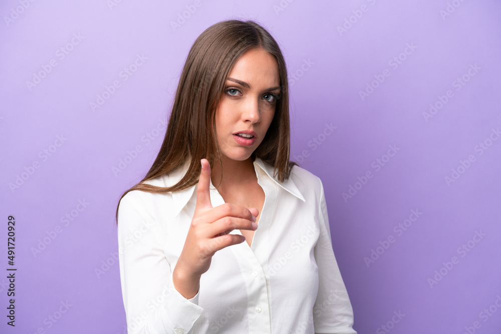 Young caucasian woman isolated on purple background frustrated and pointing to the front Young caucasian woman isolated on purple background frustrated and pointing to the front