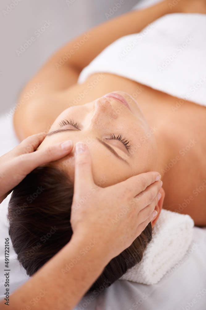 Retreating to a place of quiet relaxation. A young woman lying in a beauty spa receiving a relaxing head massage.