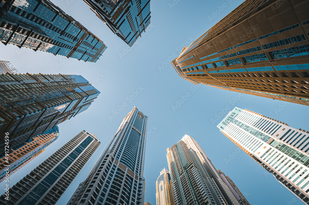 Modern glass skyscrapers in Dubai with blue sky in background. Impressive architecture of financial district and Dubai marina.