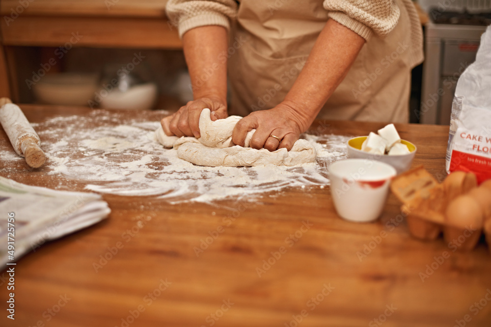 Fototapeta premium Made with love.... A cropped view of hands working the dough while baking in a kitchen.