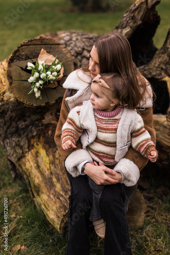 Mouther and daughter sitting on a tree and looking one way.Flower on backgraund. photo