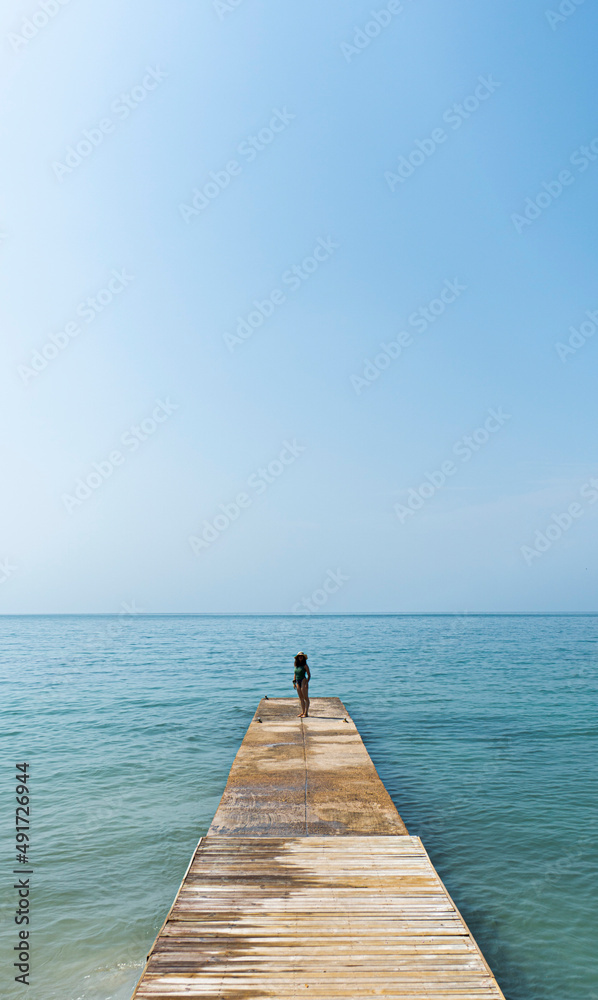 woman walking on the beach on the pier in the sand enjoying the sun and sand