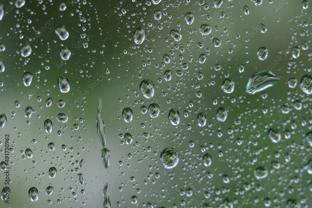 Close-up on water drops on glass under the rain.