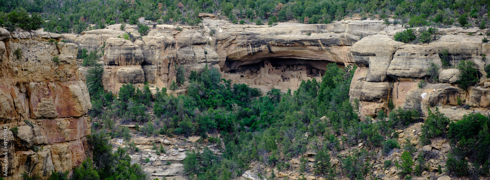 Panoramic image of Native American cliff dwellings on the side of a cliff
