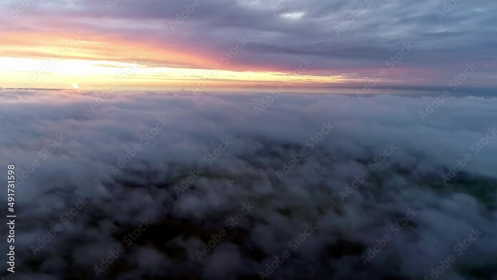 Aerial flight over cloudscape during bright golden sunset at horizon during cloudy day - view from airplane window Aerial flight over cloudscape during bright golden sunset at horizon during cloudy day - view from airplane window