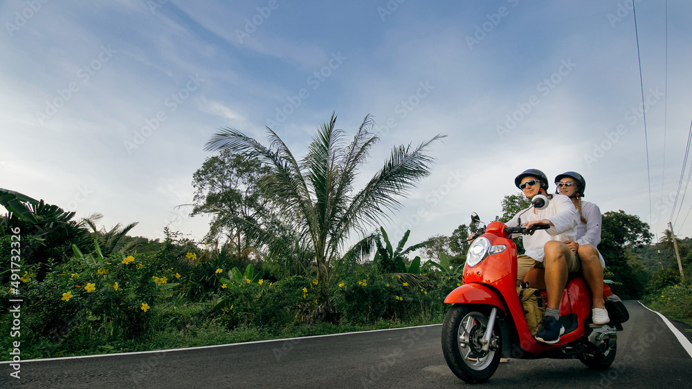 Scooter road trip. Love couple on red motorbike in white clothes on forest road trail. Just