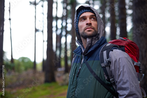 Hiking in the wild. Portrait of a young man wearing a backpack while hiking in the forest.