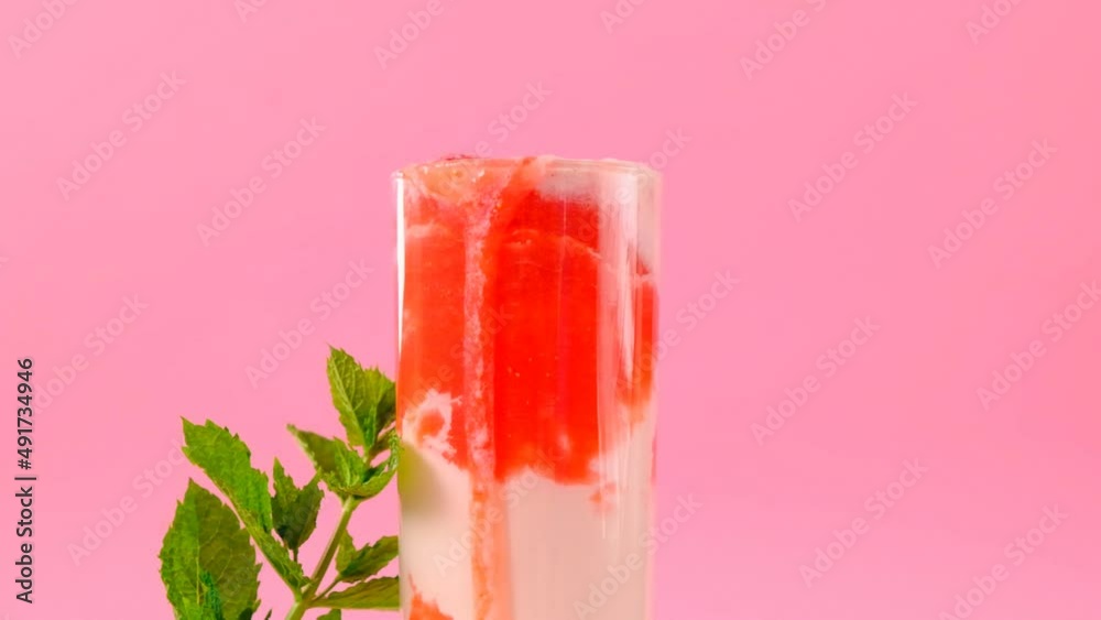 smoothies. Drink from summer berries and milk .Pink cocktail and cream in a transparent glass goblet with strawberries and sprigs of mint on a pink background.Summer cocktails and drinks.4k footage smoothies. Drink from summer berries and milk .Pink cocktail and cream in a transparent glass goblet with strawberries and sprigs of mint on a pink background.Summer cocktails and drinks.4k footage