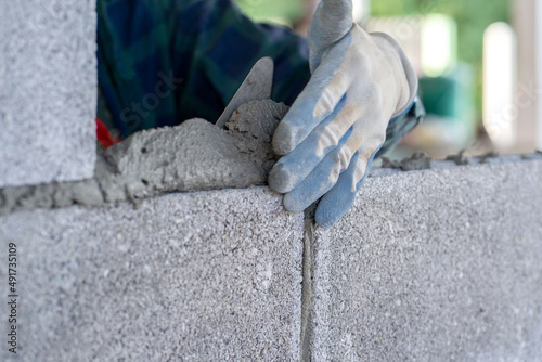 masonry worker make concrete wall by cement block and plaster at construction site