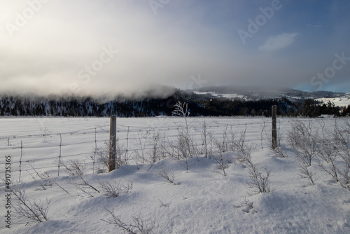a fence in a snow covered field in the mountains