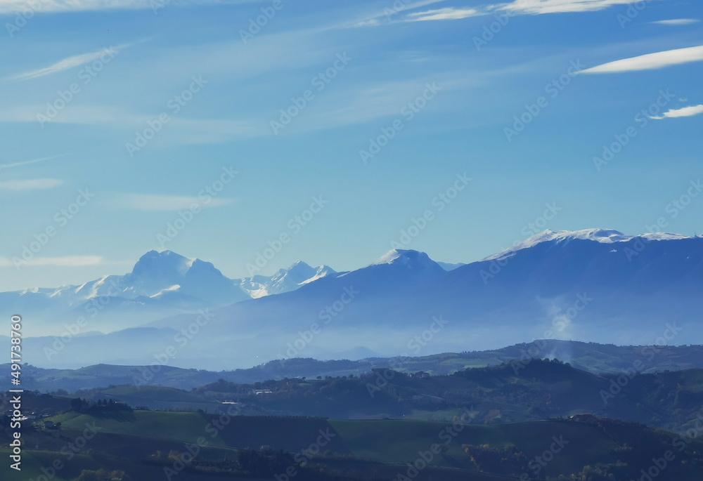 Montagne innevate e vallate nel cielo azzurro in una tersa giornata di sole invernale