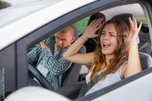 Frightened young girl driving car with two scared male passengers. Concept of inept driver and risk of accident on road © JackF