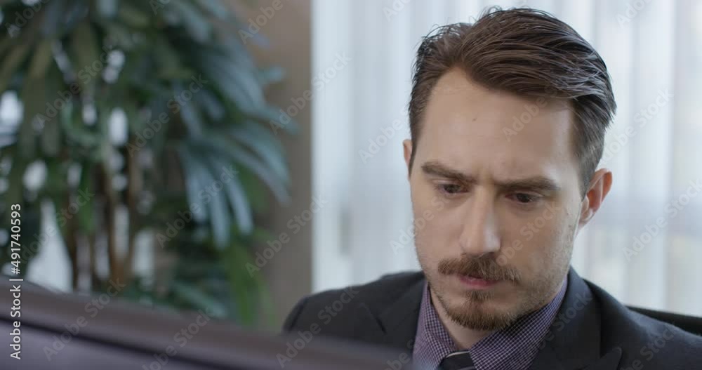 Closeup tripod shot of a corporate serious brunette man angrily typing on a desktop computer at work front of a naturally lit office window. 35mm, filmed in 4K. Closeup tripod shot of a corporate serious brunette man angrily typing on a desktop computer at work front of a naturally lit office window. 35mm, filmed in 4K.