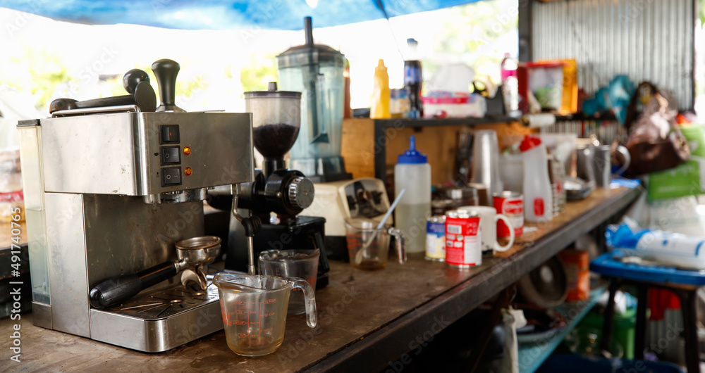 Disordered old small local dirty coffee shop wood bar counter interior design with espresso americano making machine, blender, grinder, sweeten condensed milk and other material ingredient equipment Disordered old small local dirty coffee shop wood bar counter interior design with espresso americano making machine, blender, grinder, sweeten condensed milk and other material ingredient equipment