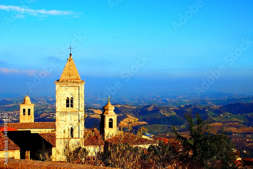 Upper part of an Italian catholic church with beautiful hilly landscape in the background under the blue sky in Penna San Giovanni