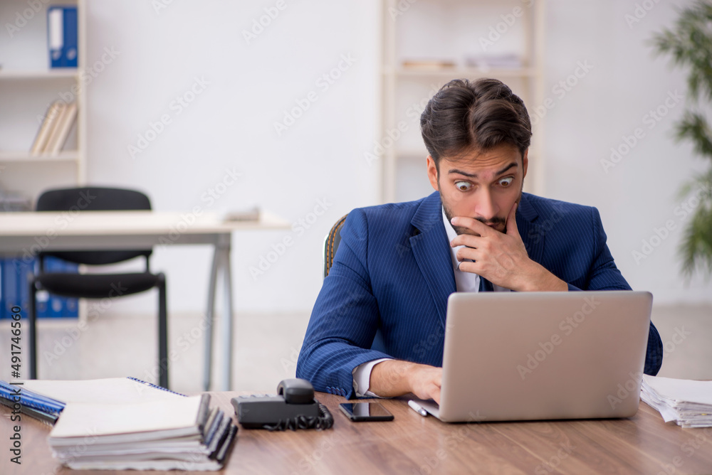 Young male employee unhappy with excessive work in the office