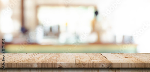 Wooden table top with blurred people in coffee shop and cafe background for display montage  copy space.
