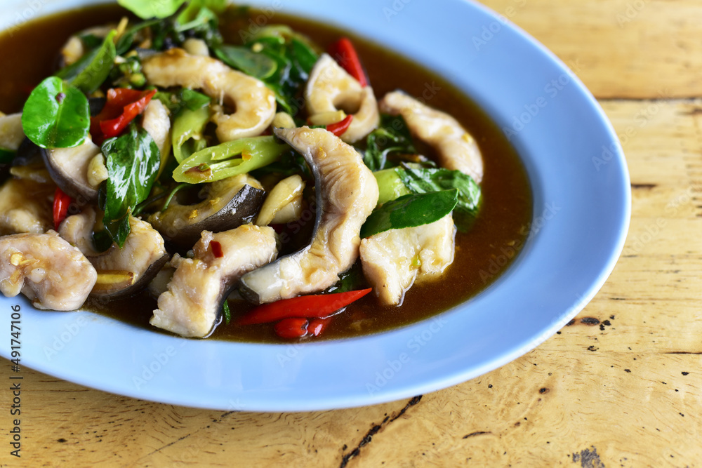 Close up Stir-fried fish (Hemibagrus wyckioides) with herbs and spices on wooden table. Authentic Thai food. Close up Stir-fried fish (Hemibagrus wyckioides) with herbs and spices on wooden table. Authentic Thai food.