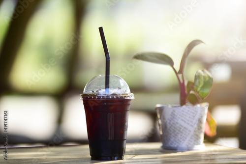 Close up of take away plastic cup of iced black coffee (Americano) on wooden table.