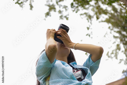 Fotógrafa revisando su cámara con cielo despejado photo