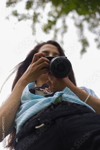 Fotógrafa revisando su cámara con cielo despejado photo