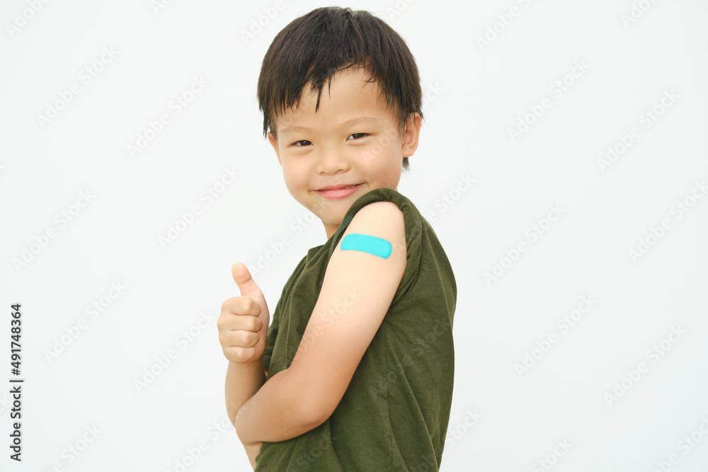 Adhesive bandage on arm after covid-19 vaccination,Thump up, Little kid showing his arm with bandage after receiving vaccination, COVID 19 vaccine for children and youth, Back to school concept Adhesive bandage on arm after covid-19 vaccination,Thump up, Little kid showing his arm with bandage after receiving vaccination, COVID 19 vaccine for children and youth, Back to school concept