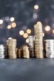 stacks of different golden and silver coins creating a big amount of savings shot on dark background with fairy light, abundance and reaching your savings goals