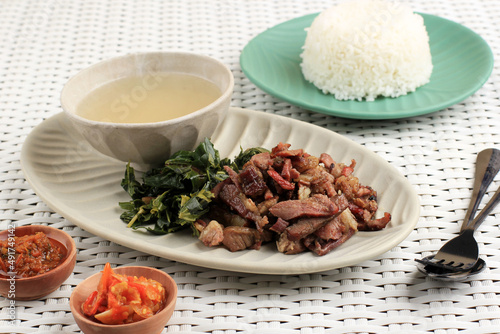 Se'i Sapi or  Beef Sei is Indonesia Traditional Smoked Beef, Served with Boiled Cassava Leaves and Sambal Luat or Sambal Matah. photo
