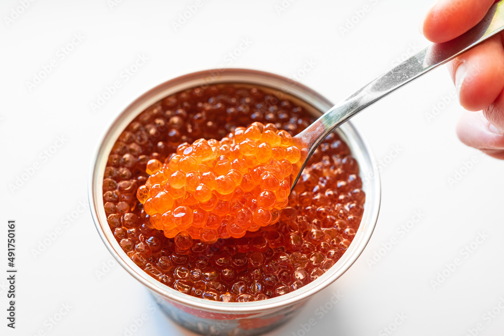 a spoonful of salted red caviar is taken out of the jar. delicacy. delicious canned fish. a traditional Russian snack for a festive banquet.