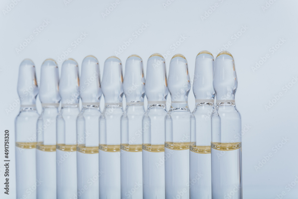 Glass medical ampoule vial for injection. Medicine is liquid sodium chloride with of aqueous solution in ampulla. Close up. Bottles ampule multicolor on background color and water. Human plasma. Glass medical ampoule vial for injection. Medicine is liquid sodium chloride with of aqueous solution in ampulla. Close up. Bottles ampule multicolor on background color and water. Human plasma.