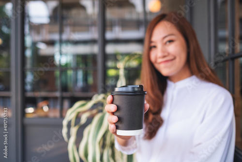 Portrait image of a beautiful young asian woman holding and drinking hot coffee in paper cup
