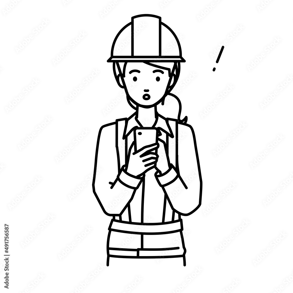 立ってスマートフォンを操作して何かに気づいて驚いた工事現場の女性 立ってスマートフォンを操作して何かに気づいて驚いた工事現場の女性