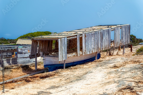 Traditional way of keeping small fishing boats under old wooden shad while on land in Formentera, Spain. © Goran