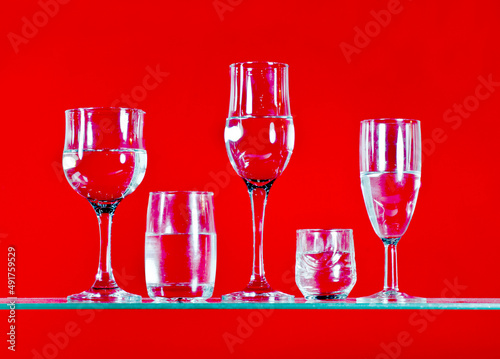 arious drinks filled with water are placed on a bright red background photo